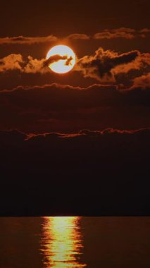 Nefes kesen bir gün batımı sahnesi, sakin suların üzerinde bir dizi sıcak rengi güzel bir şekilde yansıtıyor.