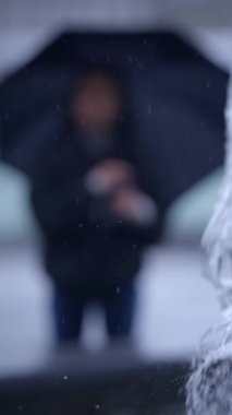 Bulanık bir görüntü, elinde şemsiye tutan bir adamı yağmurlu bir günün özünü etkili bir şekilde iletirken yakalar.