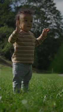 Neşeli küçük bir çocuk yemyeşil bir tarlada mutlu bir şekilde duruyor güneşli bir günde doğanın güzelliğinin tadını çıkarıyor.