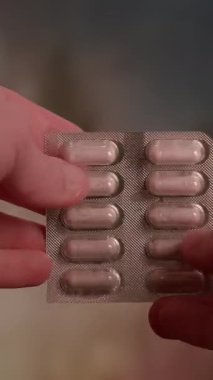Çeşitli kapsüllerle dolu bir su toplayıcı paketini tutan bir kişinin detaylı ve yakın görüntüsü