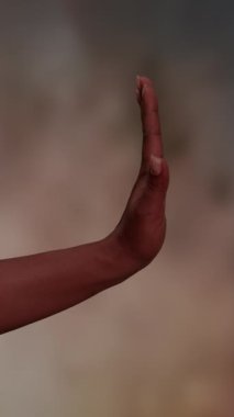 Bulanık bir arkaplana karşı dur ya da dur işareti koymak için kaldırılmış bir insan elinin detaylı yakın plan görüntüsü.