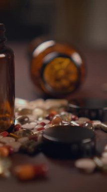 Altüst olmuş bir şişe ahşap bir yüzeye çeşitli renkli haplar ve tabletler döküyor.