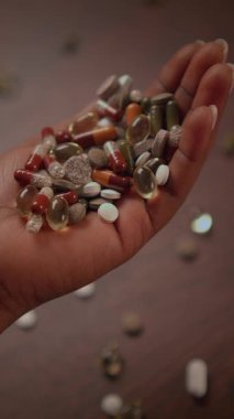 Yakın plan çekimde, doğal taşlarla renkli hapları tutan, sağlık ve sağlık temalarını vurgulayan bir el görülüyor.