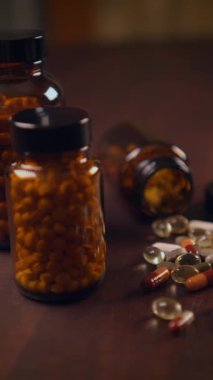 Renkli ilaç şişeleri ve kırsal ahşap bir masa yüzeyinde sergilenen çeşitli haplar.