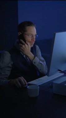 Kendini işine adamış bir profesyonel, bilgisayarın başında çalışırken aynı anda gecikme çağrısında bulunur.