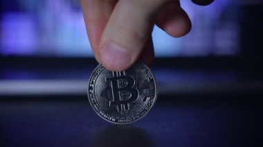 Şifreleme para eğilimlerini temsil eden bulanık dijital arkaplan karşısında Bitcoin para tutan bir el.
