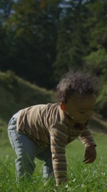 Neşeli bir çocuk mutlu bir şekilde etrafı doğayla çevrili canlı yeşil bir alanda geziyor ve aktif olarak oynuyor.