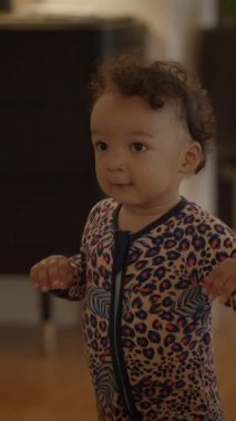 Sevimli bir leopar desenli tulum giymiş neşeli ve neşeli bir çocuk, neşeli bir şekilde kapalı bir alanı keşfediyor.