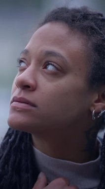 Güzel rastalı bir kadın düşünceli bir şekilde yukarı bakar, derin bir iç gözlem anını yakalar.