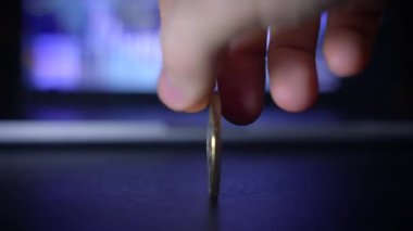 Parlak bir Bitcoin sikkeyi kavrayan, arkasında bulanık ve dijital bir ekran bulunan bir elin detaylı bir yakın çekimi.