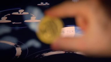 Yüksek teknolojili bir oyun arayüzünün üzerinde parlayan bir madeni parayı tutan bir kişinin ayrıntılı yakın çekimi