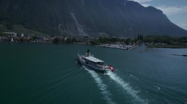 Göz kamaştırıcı bir dağ manzarasında güzel bir göl boyunca süzülen bir teknenin sükunetini hissedin.