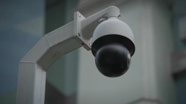 Gösterişli bir güvenlik kamerası bulanık bir arkaplana karşı duruyor ve izleyenlerin dikkatini çekiyor.