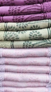 Pembe, yeşil ve eflatun renkli katlanmış havlular yığını