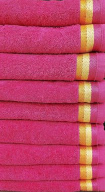 Sarı geometrik çizgili pembe banyo havluları katlandı ve istiflendi.