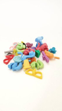 Farklı şekil ve tasarımlarda renkli silikon bardak işaretleri beyaz bir yüzeye yerleştirilmiştir. İşaretler kırmızı, mavi, yeşil, sarı ve mor gibi parlak tonları içerir, her biri fincanlara kolay bağlanmak için bir kanca veya döngü tasarımı ile.