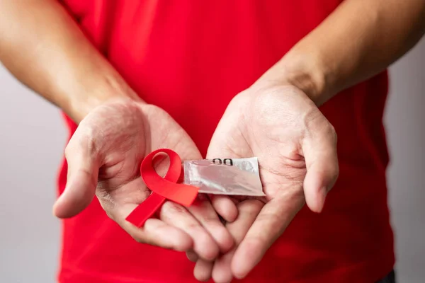 12月世界エイズデー赤いリボンとコンドーム 取得免疫不全症候群 安全性性性性性とヘルスケアの概念 — ストック写真