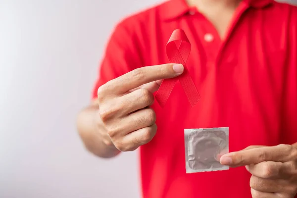 12月世界エイズデー赤いリボンとコンドーム 取得免疫不全症候群 安全性性性性性とヘルスケアの概念 — ストック写真
