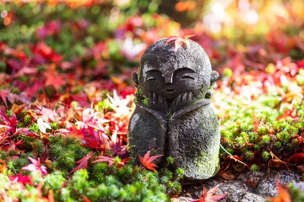 Japonya, Kyoto 'daki Enkoji Tapınağı' ndaki Japon bahçesinde düşen kırmızı akçaağaç yaprağıyla Japon Jizo heykel bebeği. Sonbahar mevsiminde önemli ve ünlüdür.