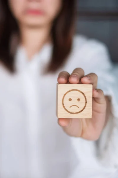 stock image Woman holding angry emotion face block. Customer choose Emoticon for user reviews. Service rating, mental health, positive thinking, satisfaction, evaluation and feedback concept