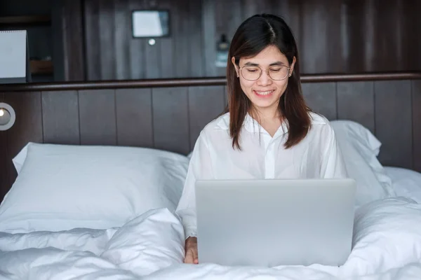 Happy woman using laptop for work, female meeting  online by computer notebook on bed. technology, network, work from home, lifestyle and digital communication concept