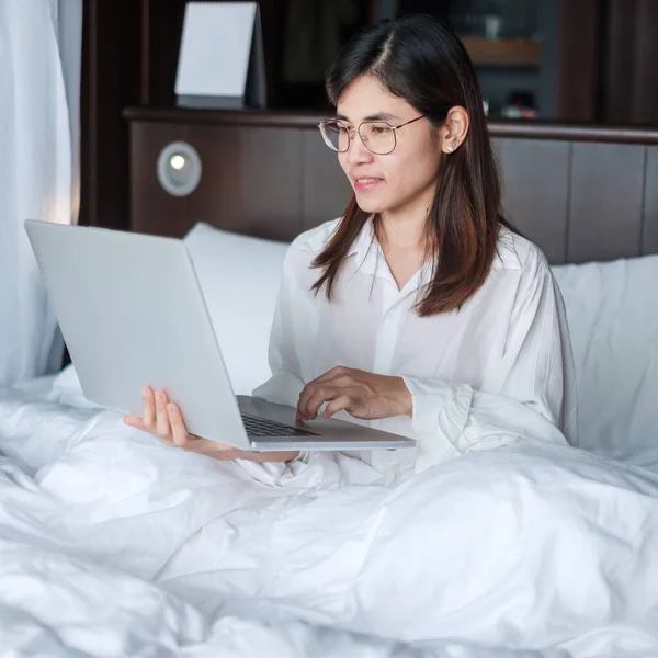 Happy woman using laptop for work, female meeting  online by computer notebook on bed. technology, network, work from home, lifestyle and digital communication concept