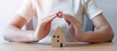 İş kadını el kaplaması ahşap ev modeli. gayrimenkul, konut sigortası, enflasyon, ekonomik durgunluk ve mülkiyet kavramları