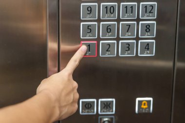 El parmağı asansör düğmesine basıyor, kadın ofisteki veya dairedeki asansörü kullanıyor.