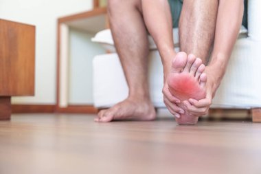Plantar fasiiti ve ayak parmakları yüzünden yalın ayak ağrısı çeken ya da dar ayakkabılar giydiği için su toplayan ve uzun süre koşan bir adam. Sağlık ve Tıp Konsepti