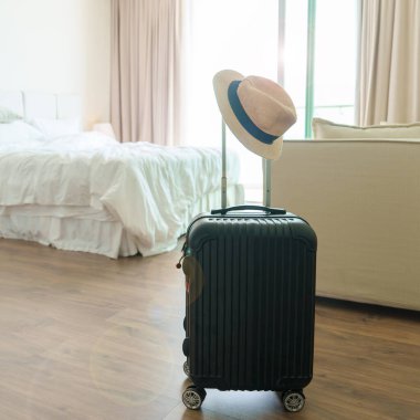 Kapı açıldıktan sonra modern otel odasında şapkası olan siyah bir bavul. Zamanın yolculuk, hizmet, yolculuk, gezi, yaz tatili ve tatil kavramları için bagajlar