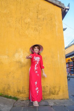 Mutlu kadın Ao Dai Vietnamlı elbisesi ve şapkası giyiyor, Hoi 'yi geziyor Vietnam' ın merkezinde antik bir kasabayı geziyor. Tarihi bir yer ve turistik yerlerin gözdesi. Vietnam ve Güneydoğu seyahat kavramı