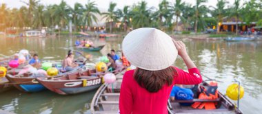 Ao Dai Vietnamlı elbisesi giyen mutlu bir kadın Thu Bon Nehri 'ni ve Hoi An antik kasabasında tekne gezintisini ziyaret ediyor. Vietnam ve Güneydoğu seyahat konsepti turizm için dönüm noktası