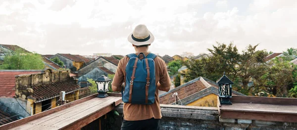 happy solo traveler traveling at Hoi An ancient town in Vietnam, man with backpack sightseeing view at rooftop.landmark and popular for tourist attractions. Vietnam and Southeast Asia travel concept