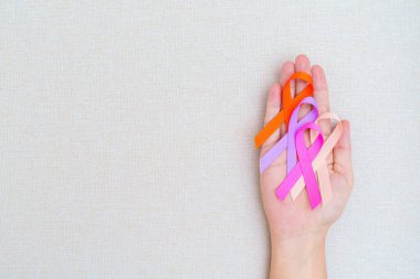 Dünya Kanser Günü, 4 Şubat. El ele tutuşmak turuncu, pembe, şeftali ve mor kurdeleler yaşayan ve hastalıkları desteklemek için. Sağlık ve Tıp Konsepti