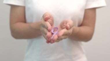 Dünya Kanser Günü, 4 Şubat. Yaşayan ve hasta insanları desteklemek için lavanta rengi bir kurdele tutan kadın. Sağlık ve Tıp Konsepti