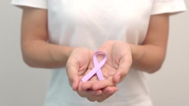 Dünya Kanser Günü, 4 Şubat. Yaşayan ve hasta insanları desteklemek için lavanta rengi bir kurdele tutan kadın. Sağlık ve Tıp Konsepti