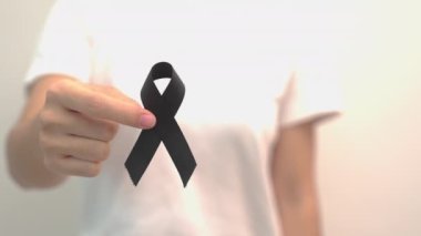 Melanoma ve cilt kanseri için siyah kurdele tutan kadın, Aşı yaralanması farkındalığı ayı, keder ve huzur içinde yatsın. Sağlık ve Irkçılık Konsepti