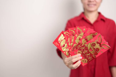 Woman holding Chinese red envelope with golden rabbit and blessing word, money gift for happy Lunar New Year holiday. Chinese sentence means happiness, healthy, Lucky and Wealthy