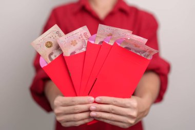 Woman holding Chinese red envelope with Thai baht money gift for happy Lunar New Year holiday