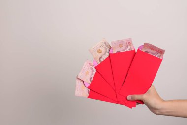 Woman holding Chinese red envelope with Thai baht money gift for happy Lunar New Year holiday