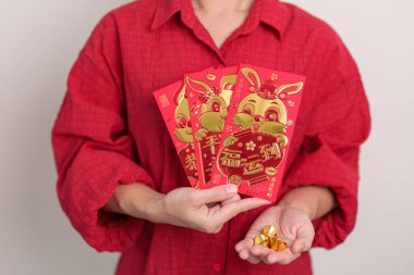 Woman holding Chinese red envelope with gold bullion, money gift for happy Lunar New Year holiday. Chinese sentence means happiness, healthy, Lucky and Wealthy