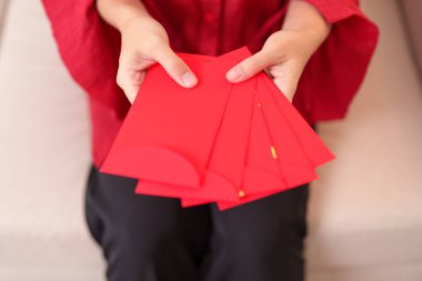 Woman holding Chinese red envelope, money gift for happy Lunar New Year holiday