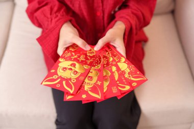 woman holding Chinese red envelope with golden rabbit and blessing word, money gift for happy Lunar New Year holiday. Chinese sentence means happiness, healthy, Lucky and Wealthy