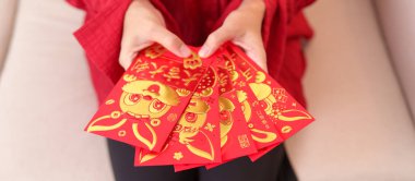 woman holding Chinese red envelope with golden rabbit and blessing word, money gift for happy Lunar New Year holiday. Chinese sentence means happiness, healthy, Lucky and Wealthy