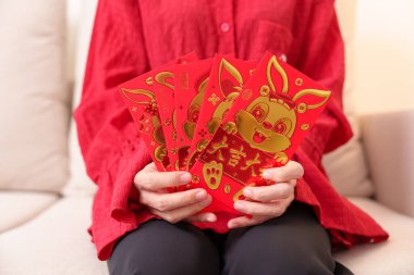 woman holding Chinese red envelope with golden rabbit and blessing word, money gift for happy Lunar New Year holiday. Chinese sentence means happiness, healthy, Lucky and Wealthy