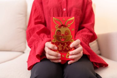 woman holding Chinese red envelope with golden rabbit and blessing word, money gift for happy Lunar New Year holiday. Chinese sentence means happiness, healthy, Lucky and Wealthy
