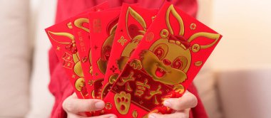 woman holding Chinese red envelope with golden rabbit and blessing word, money gift for happy Lunar New Year holiday. Chinese sentence means happiness, healthy, Lucky and Wealthy