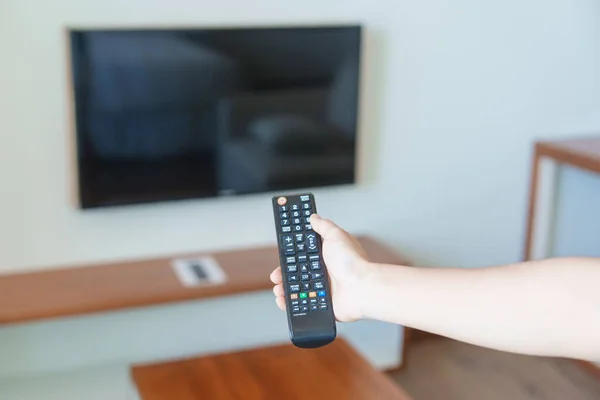 hand using remote controller for adjust Smart TV inside the modern room at home. Apartment living concept