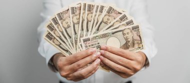 man hand holding Japanese Yen banknote stack. Thousand Yen money. Japan cash, Tax, Recession Economy, Inflation, Investment, finance and shopping payment concepts