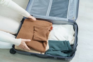 Woman hand packing her winter clothes in luggage. Time to travel, trip, Relax, spring or autumn or winter season and vacation concepts